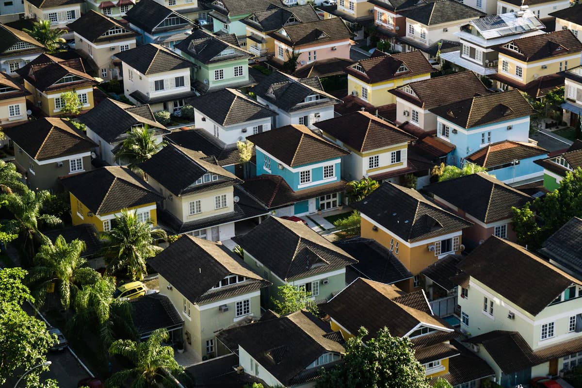 Vista aérea de un barrio residencial con casas de techos de teja y palmeras